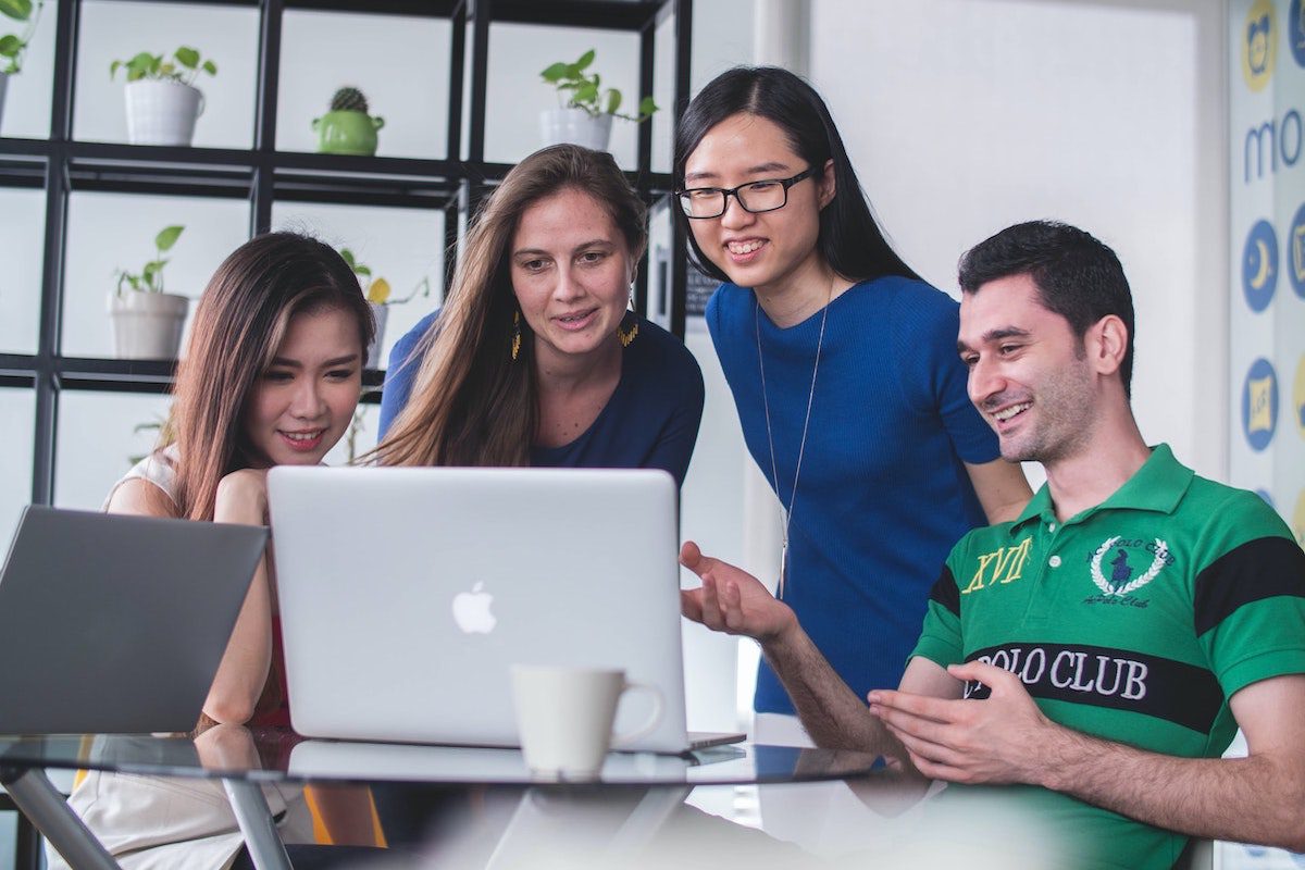 A group of coworkers gathered around a laptop computer. How To Get An Internship At Dataminr
