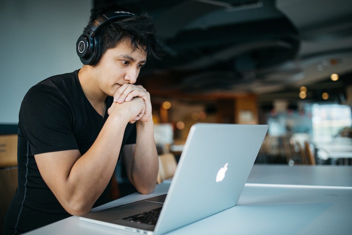Man wearing black headphones, looking at laptop screen studying online bachelor’s degree. What is a Bachelor's Degree: A Guide to College Majors