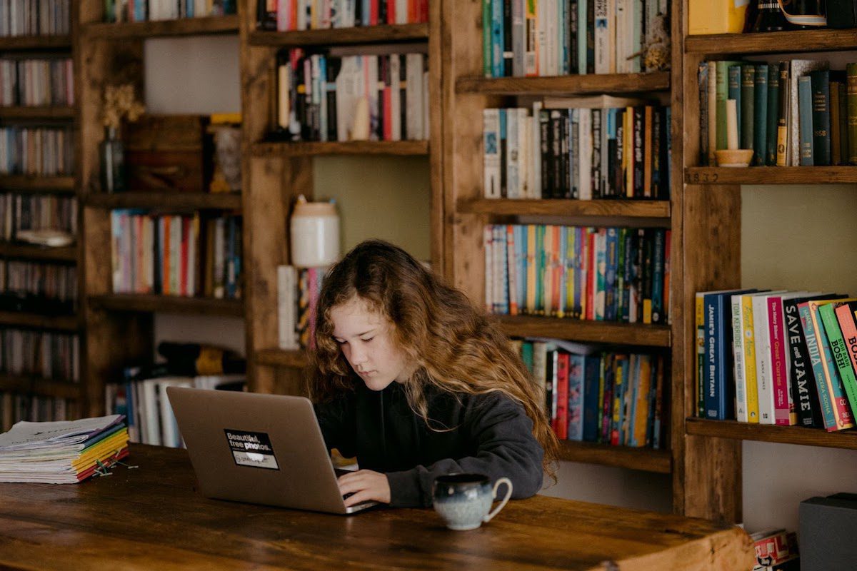 A young girl in a black shirt using a laptop
